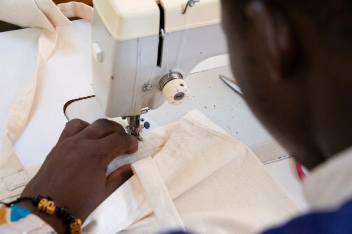 Tiraogo en train de coudre la dernière anse d’un sac en coton Tiraogo en train de coudre la dernière anse d’un sac en coton