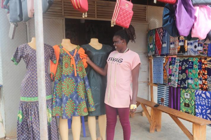 Medina showing off some of the dresses she tailored. © Enabel Uganda