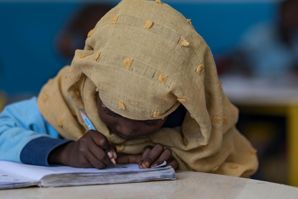 La petite Nima est très concentrée sur son travail dans une salle de classe du camp de réfugiés d’Ali Addeh